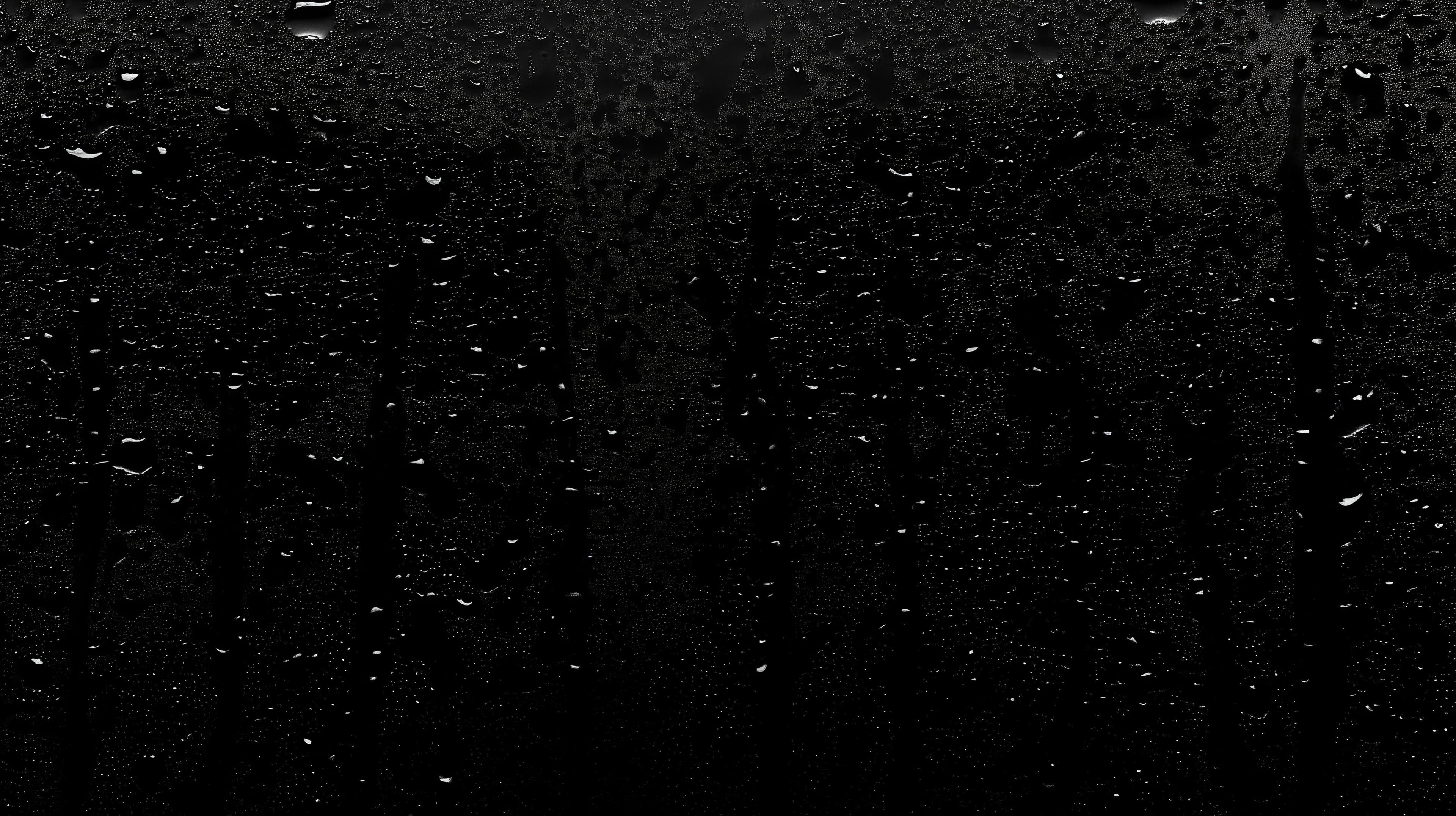 Black and white photograph of raindrops on a window. the raindrops are scattered across the surface of the window, creating a textured pattern.